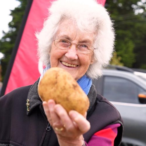 A woman enjoying the Thorpdale Potato Festival looks at the camera while holding a potato